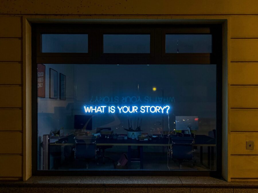 "What is Your Story" sign in office window. By Etienne Girardet via Unsplash